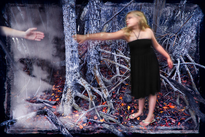 Woman in a dark dress reaching toward a hand among mangrove roots